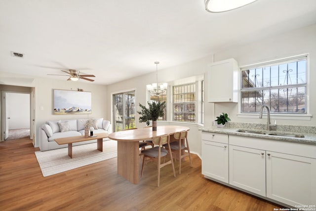 dining room featuring ceiling fan with notable chandelier, light hardwood / wood-style floors, and sink