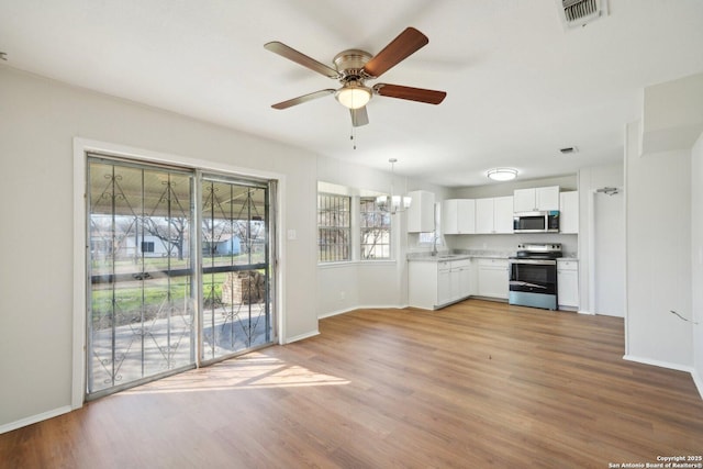 unfurnished living room with ceiling fan with notable chandelier and wood-type flooring