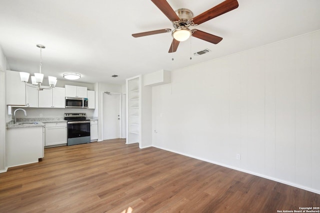 kitchen with stainless steel appliances, hardwood / wood-style floors, sink, white cabinets, and pendant lighting