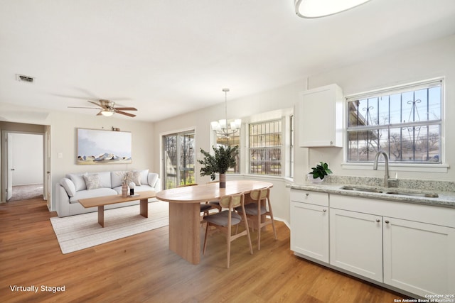 dining room with sink, ceiling fan with notable chandelier, and light hardwood / wood-style flooring