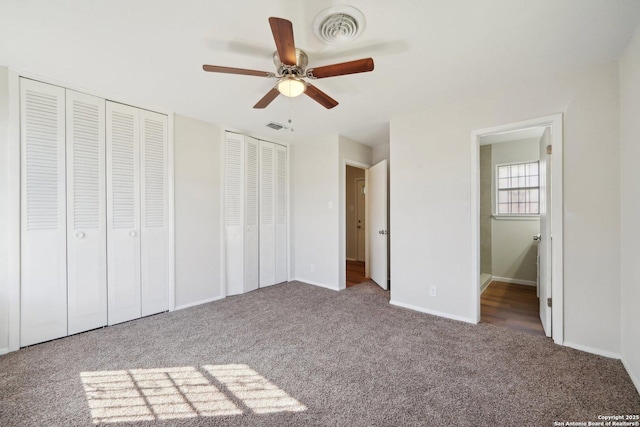 unfurnished bedroom featuring ceiling fan, multiple closets, and carpet floors