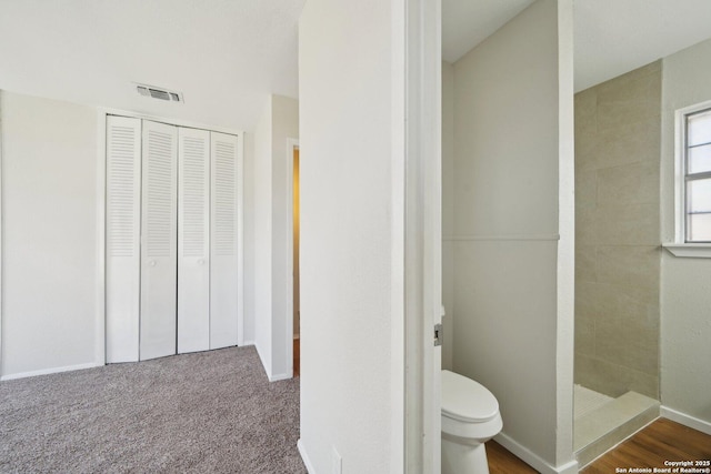 bathroom featuring tiled shower and toilet