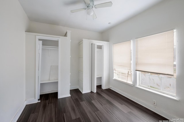 unfurnished bedroom with multiple closets, dark wood-type flooring, and ceiling fan