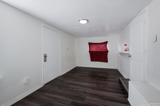 empty room with a textured ceiling and dark hardwood / wood-style floors