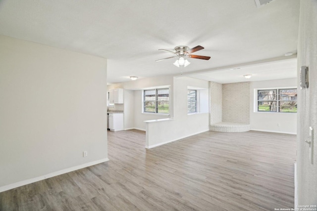 unfurnished living room with ceiling fan, light hardwood / wood-style flooring, and a textured ceiling