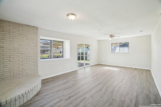 unfurnished living room with ceiling fan, wood-type flooring, brick wall, and a textured ceiling