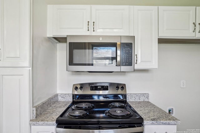 kitchen with white cabinets, stainless steel appliances, and light stone countertops