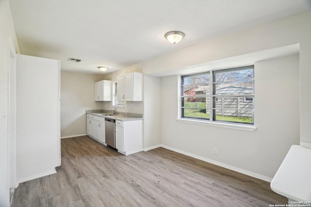 kitchen featuring sink, dishwasher, white cabinets, and light wood-type flooring