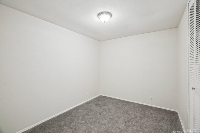 spare room with a textured ceiling and dark carpet