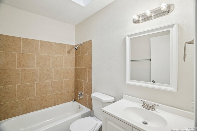 full bathroom featuring toilet, a skylight, tiled shower / bath, and vanity