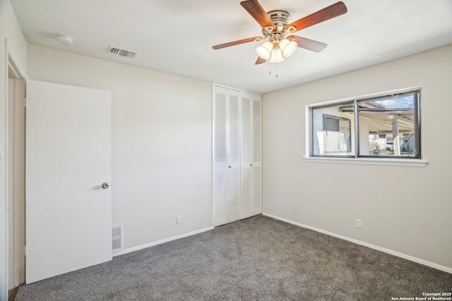 unfurnished bedroom with ceiling fan, dark colored carpet, and a closet