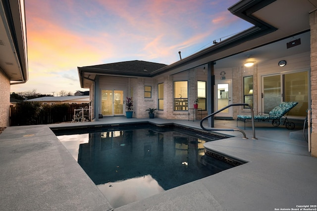 pool at dusk with a patio area