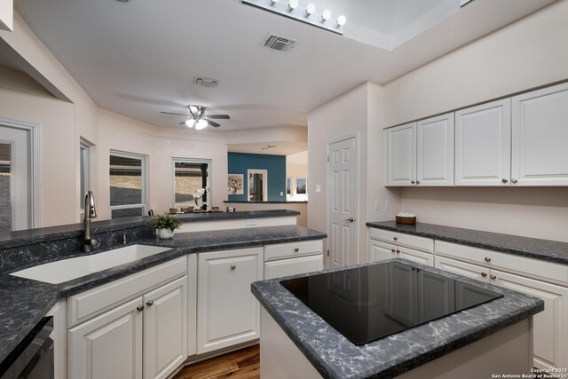 kitchen with white cabinetry, sink, black appliances, and a center island