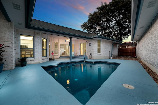 pool at dusk with a patio area