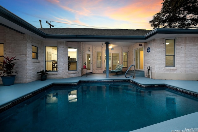 pool at dusk with a patio area