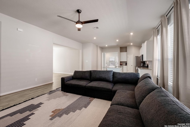 living room featuring ceiling fan, sink, and light hardwood / wood-style floors