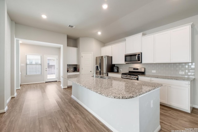 kitchen with appliances with stainless steel finishes, a kitchen island with sink, and white cabinets