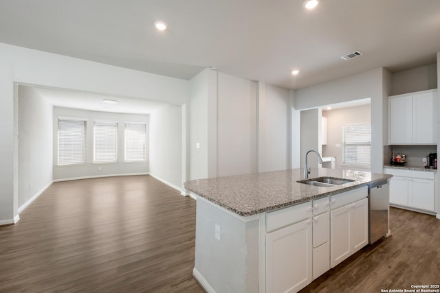 kitchen with an island with sink, light stone countertops, stainless steel dishwasher, sink, and white cabinetry