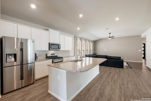 kitchen with white cabinetry, an island with sink, stainless steel appliances, sink, and vaulted ceiling