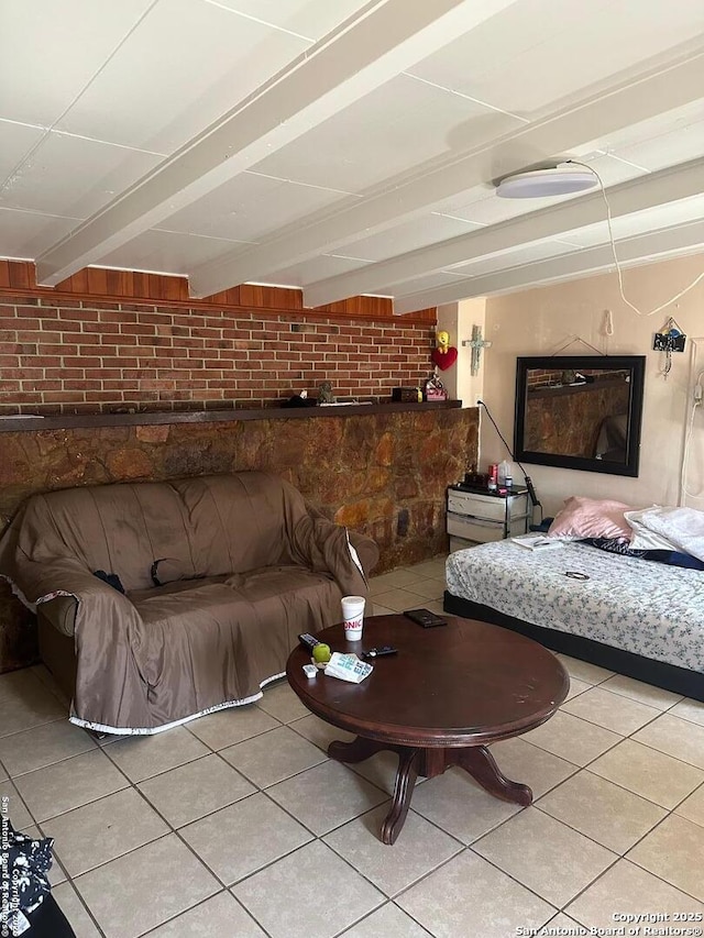 bedroom with beam ceiling, brick wall, and light tile patterned flooring