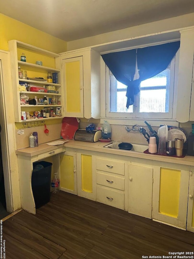 kitchen featuring white cabinets, pendant lighting, sink, and dark hardwood / wood-style flooring