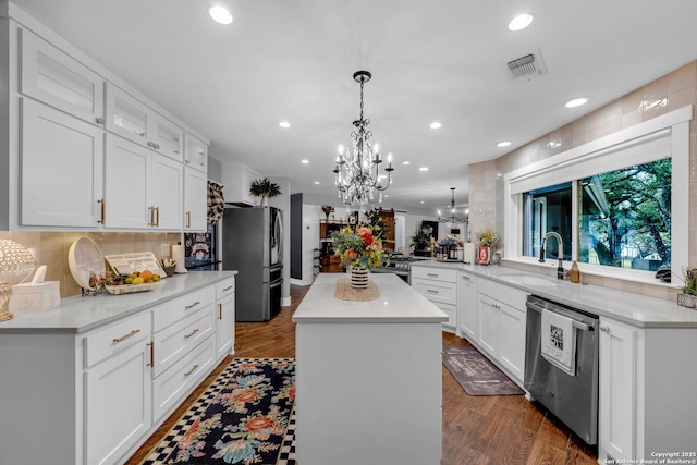 kitchen featuring sink, a center island, stainless steel appliances, kitchen peninsula, and white cabinets