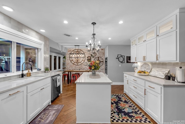 kitchen with white cabinetry, a kitchen island, sink, dishwasher, and pendant lighting