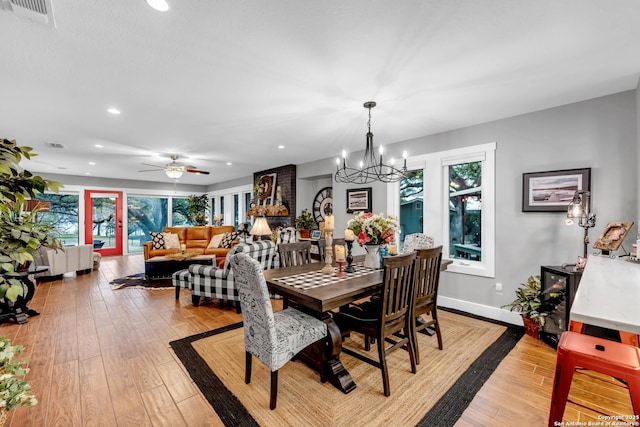 dining room featuring ceiling fan with notable chandelier and light hardwood / wood-style flooring