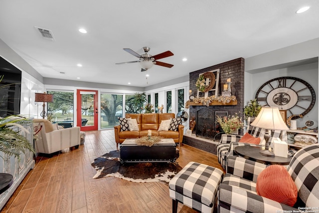 living room with a fireplace, light hardwood / wood-style flooring, and ceiling fan