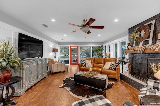 living room with light hardwood / wood-style flooring, plenty of natural light, and a fireplace