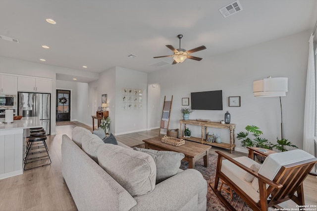 living room with ceiling fan and light hardwood / wood-style flooring