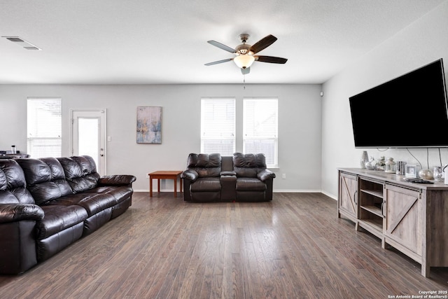 living room with ceiling fan, a wealth of natural light, and dark wood-type flooring