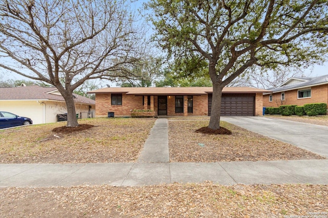 single story home featuring a garage, concrete driveway, brick siding, and covered porch