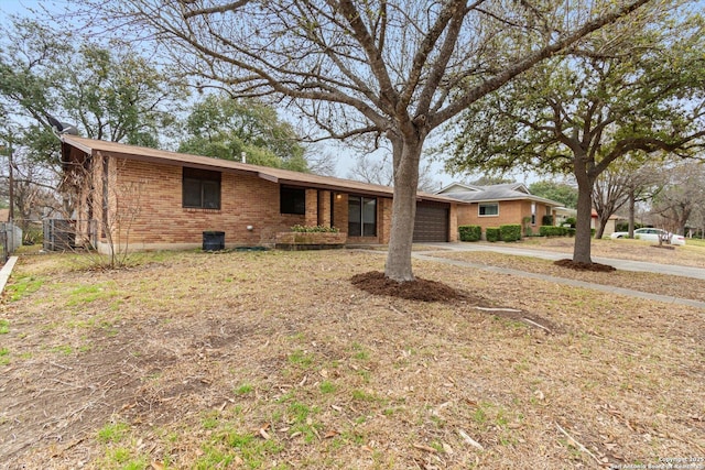 ranch-style home featuring concrete driveway, brick siding, fence, and an attached garage