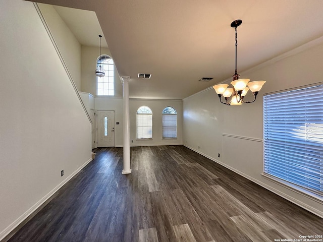 unfurnished living room with ornate columns, a chandelier, and dark hardwood / wood-style floors