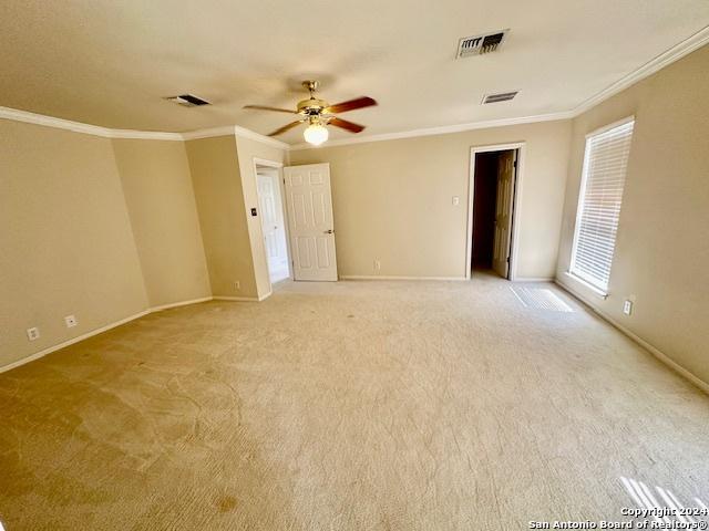 carpeted empty room featuring crown molding and ceiling fan