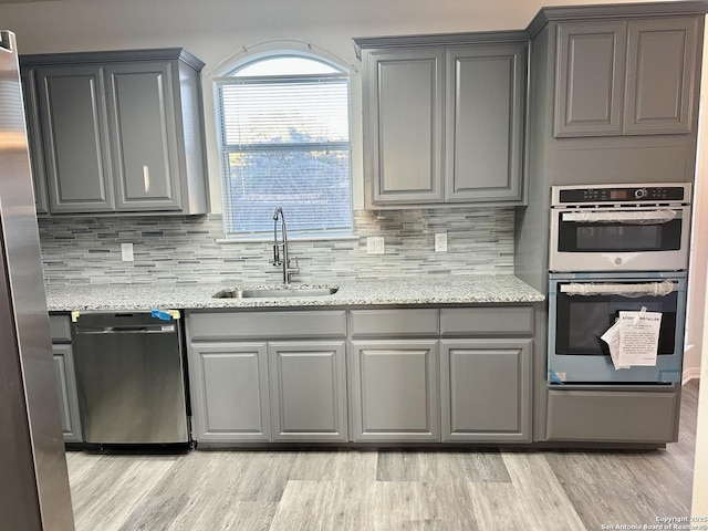 kitchen featuring sink, light stone countertops, gray cabinetry, and stainless steel appliances