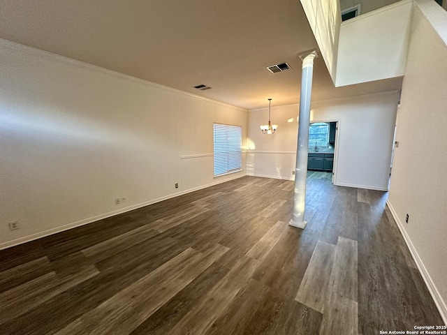 interior space with a notable chandelier, ornamental molding, dark wood-type flooring, and decorative columns