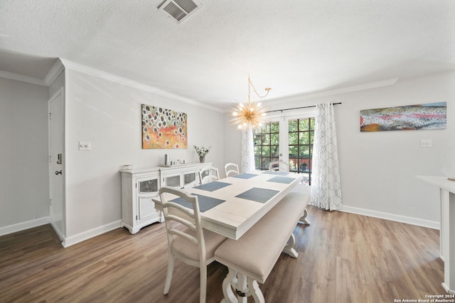 dining space featuring light wood-type flooring, a chandelier, crown molding, and a textured ceiling