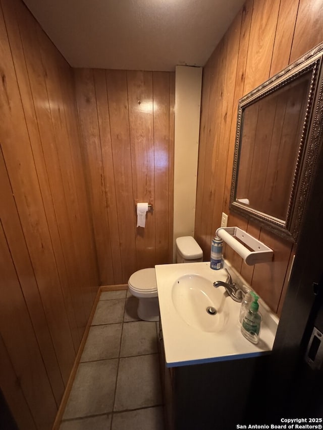 bathroom featuring wood walls, vanity, toilet, and tile patterned floors