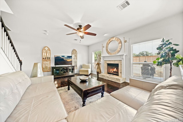 living room with a stone fireplace, ceiling fan, and wood-type flooring