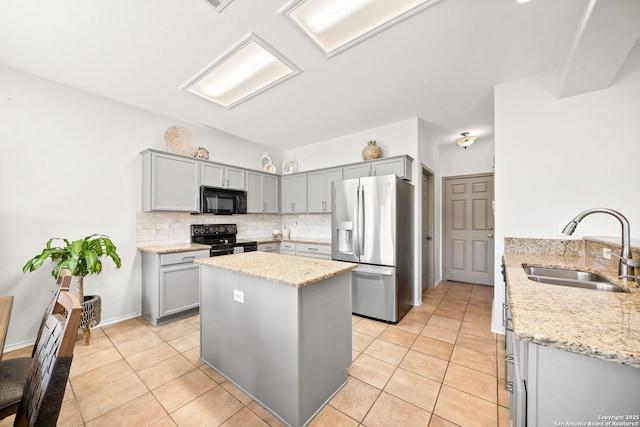 kitchen featuring decorative backsplash, sink, light stone countertops, and black appliances