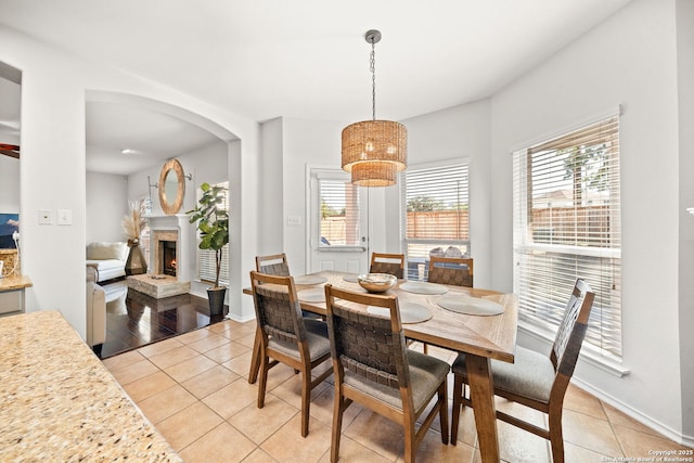 dining space featuring light tile patterned floors and a stone fireplace