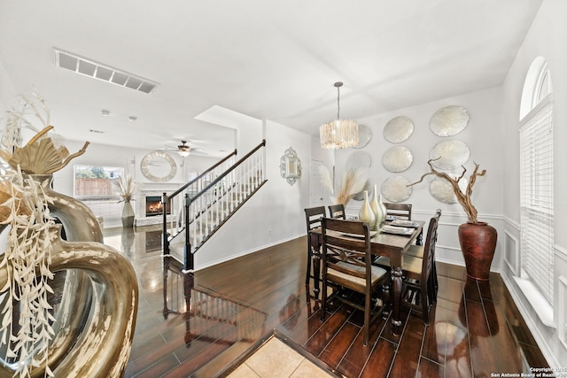 dining room with ceiling fan with notable chandelier and dark wood-type flooring