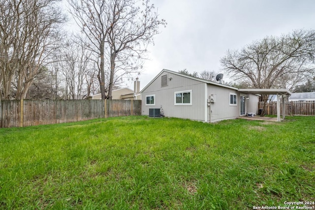 rear view of property with central AC and a yard