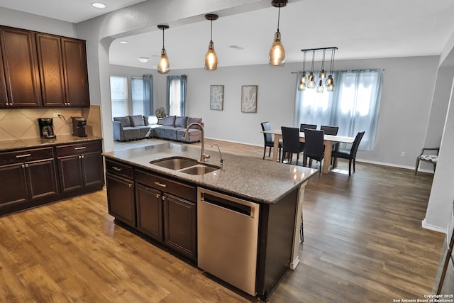 kitchen featuring dark brown cabinets, dishwasher, an island with sink, decorative light fixtures, and sink