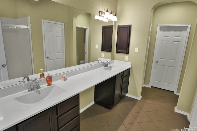 bathroom with toilet, vanity, and tile patterned flooring