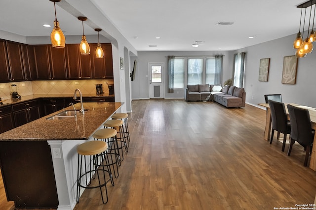 kitchen featuring pendant lighting, sink, dark stone counters, and a breakfast bar area