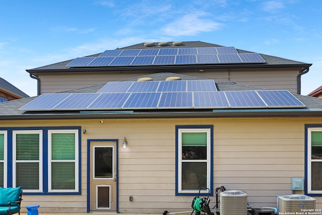 rear view of house with central AC unit and solar panels