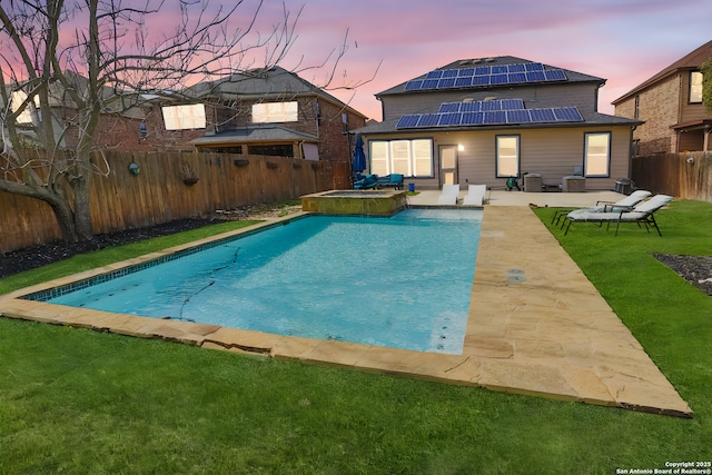 pool at dusk featuring a patio area, a yard, and an in ground hot tub